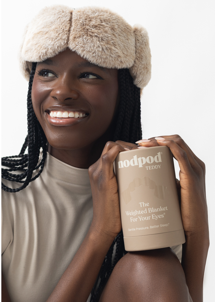 Woman wearing a beige sleep mask with a product labeled 'hoodpod' on a white background