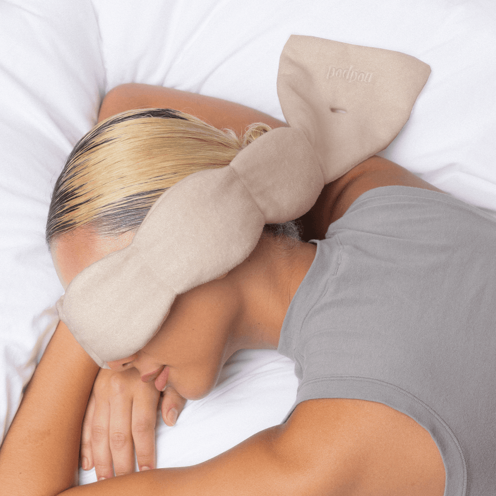 Person lying down with a beige neck pillow on a white background