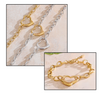 Gold and silver heart-shaped chain bracelets on a textured surface.