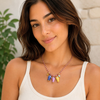 Woman wearing a fun summer necklace with colorful fish charms against a neutral background