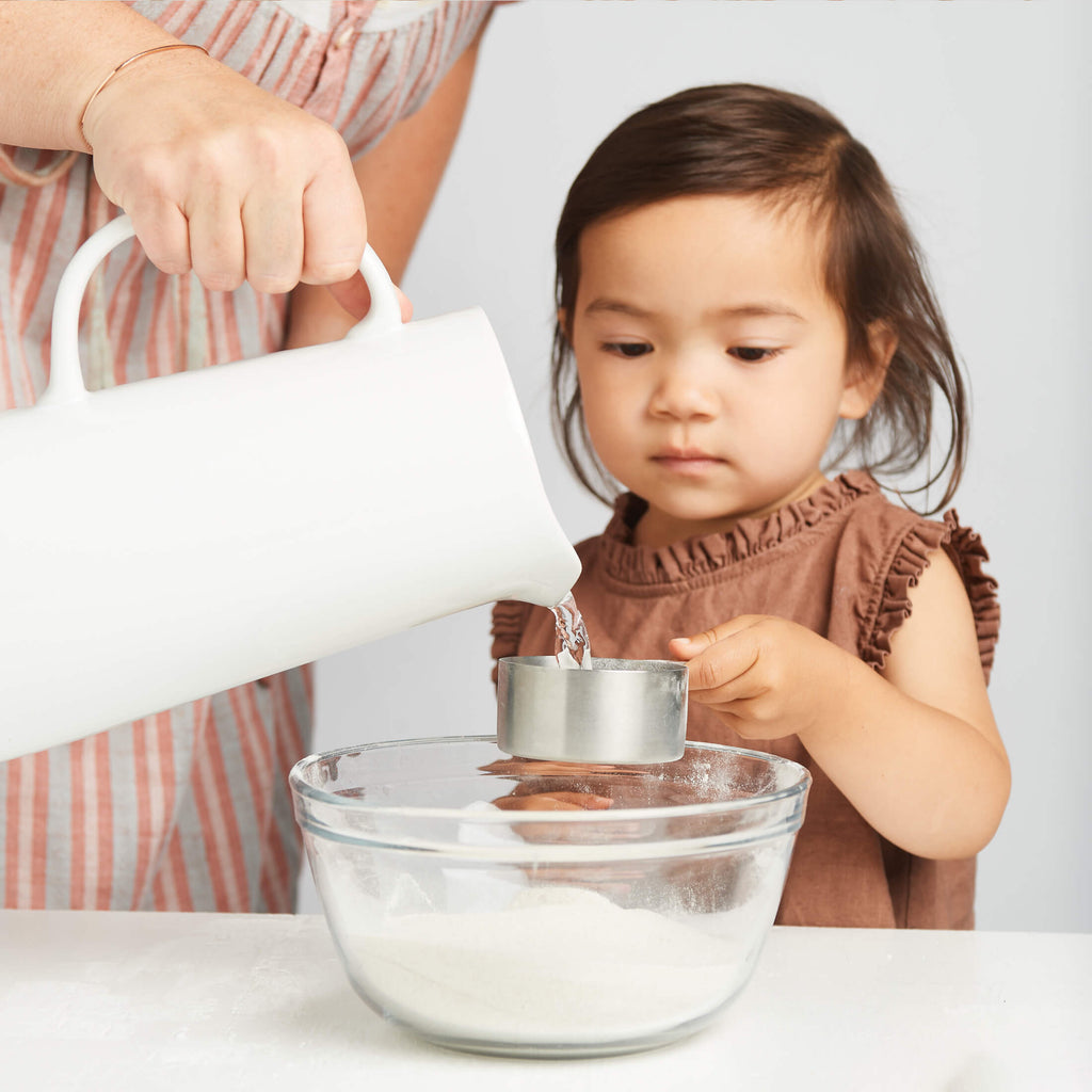 Child helping with clay kit, pouring liquid into a bowl