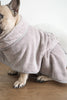 Dog wrapped in a towel on a wooden floor