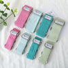 pet collars in pink, mint, teal, and light green gingham patterns are arranged on a white fabric background with a decorative green plant and a card.