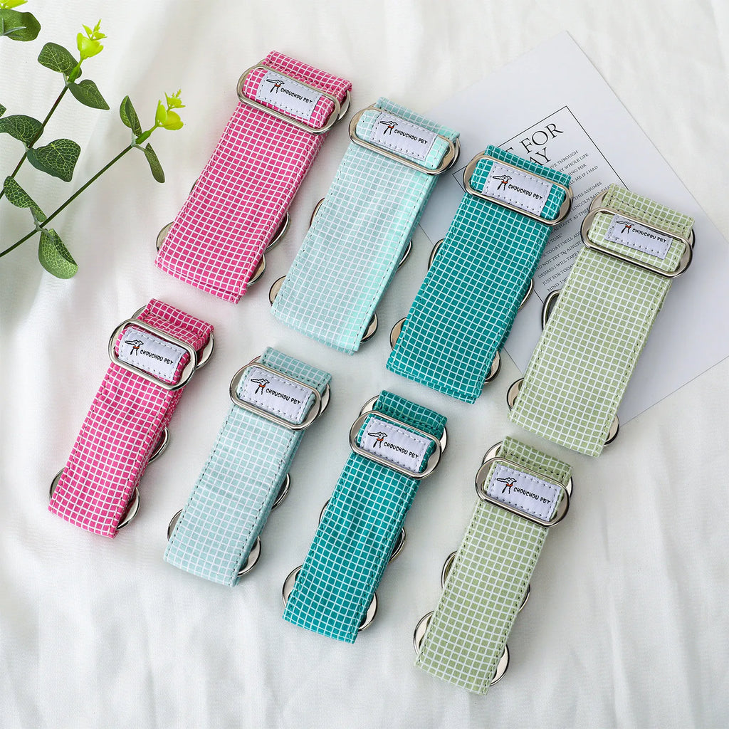 pet collars in pink, mint, teal, and light green gingham patterns are arranged on a white fabric background with a decorative green plant and a card.
