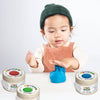 Child playing with blue play dough surrounded by eco-friendly play dough containers on a white background