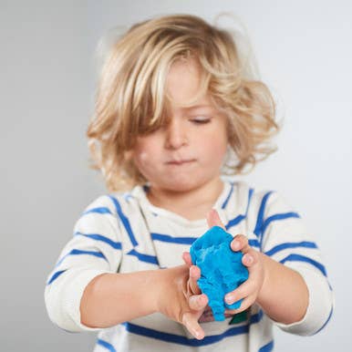 Child playing with a blue object against a plain background