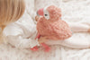 Child holding a pink flamingo plush toy on a soft surface
