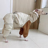 Dog wearing a beige and brown outfit indoors