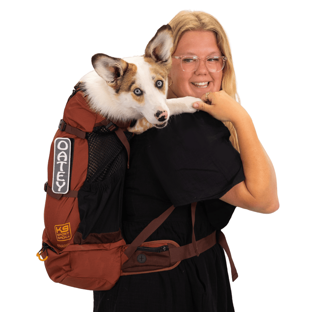 Woman holding a dog in a red backpack with 'K9 Gear' branding on a transparent background