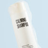 Shampoo bottle labeled 'Calming Shampoo' for dogs and cats on a light blue background