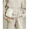 Person wearing a beige outfit with a matching waist bag on a white background