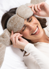 Woman wearing fluffy eye masks and ear warmers, smiling as its a great stocking stuffer