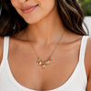 Woman wearing a gold necklace with starfish and shell charms.