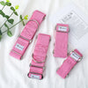 Four pink gingham dog collars with silver metal rings and buckles, arranged on a white fabric background with a decorative green plant and a printed card.