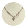 Platinum color necklace with a heart pendant on a beige circular stand