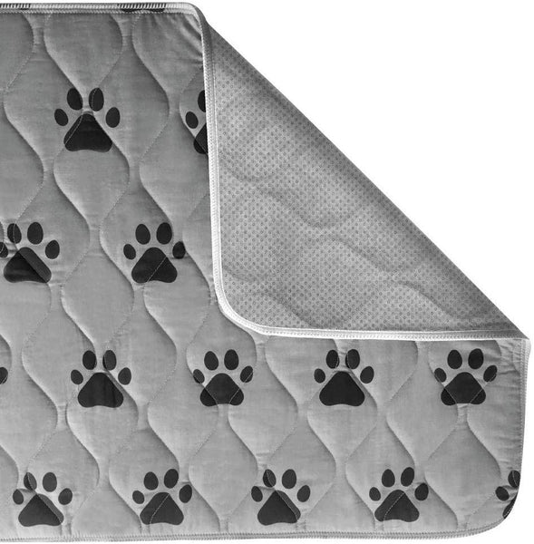 A gray puppy pad with a black paw print pattern, shown with one corner folded over to reveal a textured underside, on a white background.