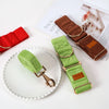 Two dog collars, one green and one brown, with gold hardware on a white surface.