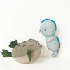 Two handmade crocheted sea creature toys on a clean white background. One is a round beige puffer fish with green fins and tail, and the other is a light blue seahorse with a bright blue tail and back.
