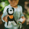 Child holding a small crocheted panda bear toy outdoors.