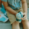 Person holding a blue and white knitted toy with a blurred background