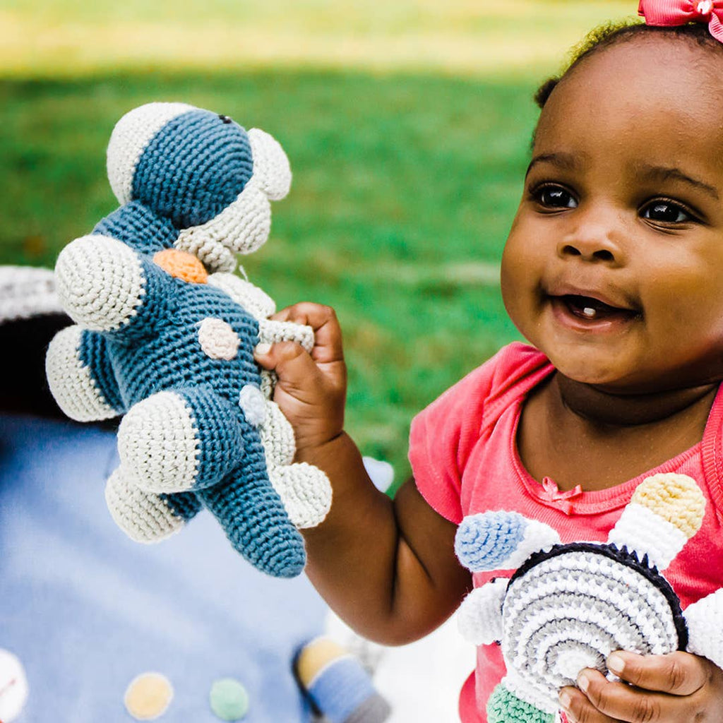 Child holding a blue and white crochet toy outdoors