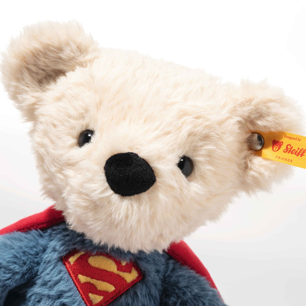 Plush bear toy with Superman cape and Steiff tag on a white background