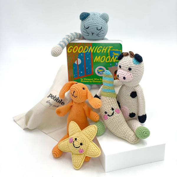 Collection of organic crocheted toys including a cat, dog, cow, and star, with a 'Goodnight Moon' book in the center.