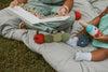 Two children sitting on a blanket with colorful toys and a book.