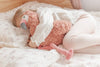 Child sleeping with a pink flamingo plush toy on a bed