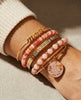 Stack of colorful bracelets on a wrist with 'mom' and decorative charms.