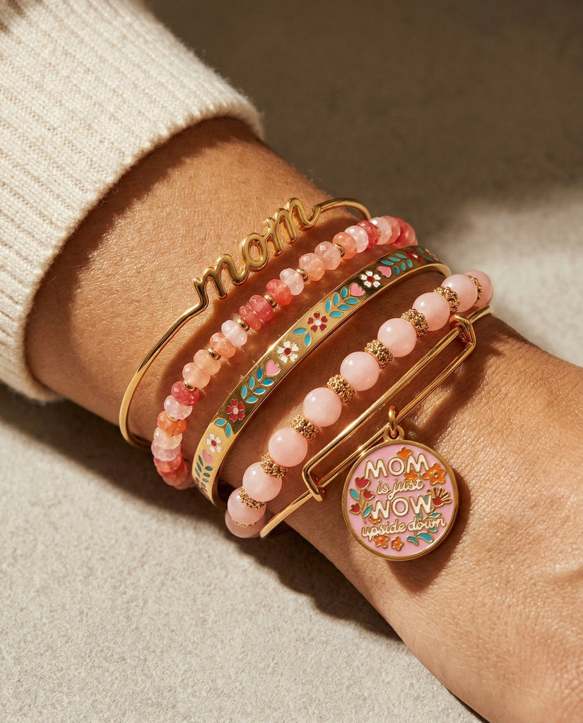 Stack of colorful bracelets on a wrist with 'mom' and decorative charms.