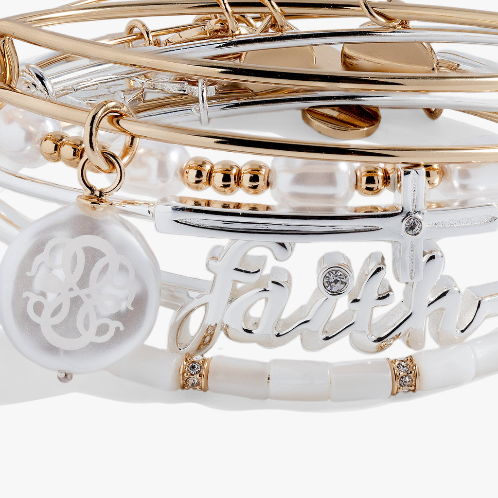 Stack of gold and silver bracelets with 'Faith' on a white background