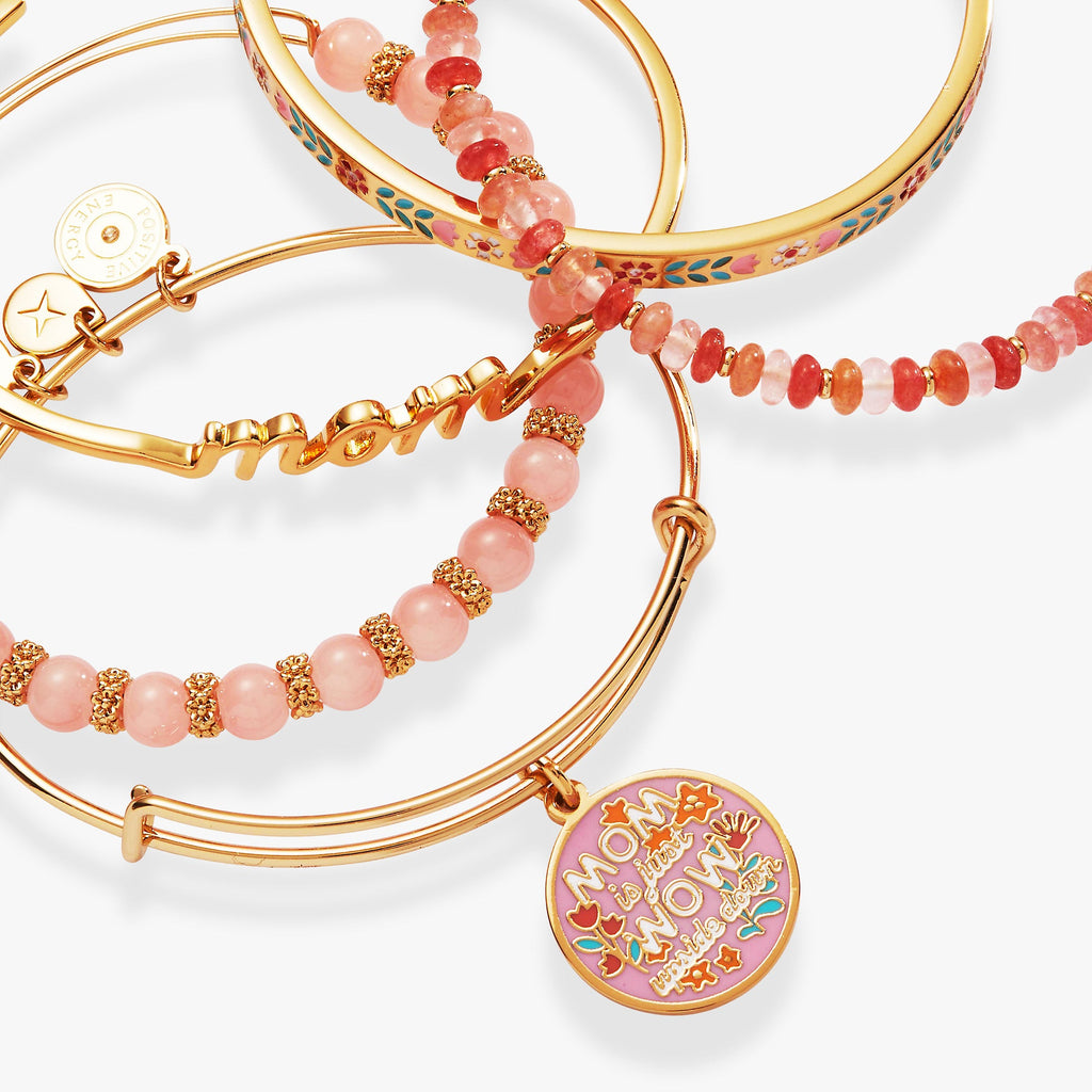 Gold bracelets with pink beads and 'Mom' charm on a white background
